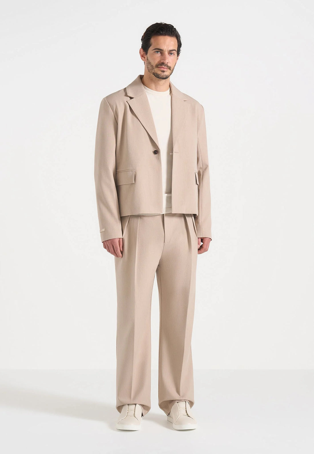 Man wearing a beige suit against a white background